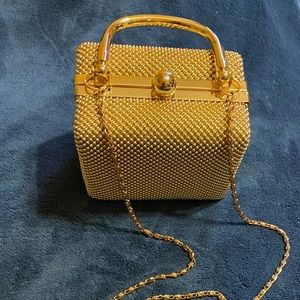 Small cube gold purse with chain shoulder strap.